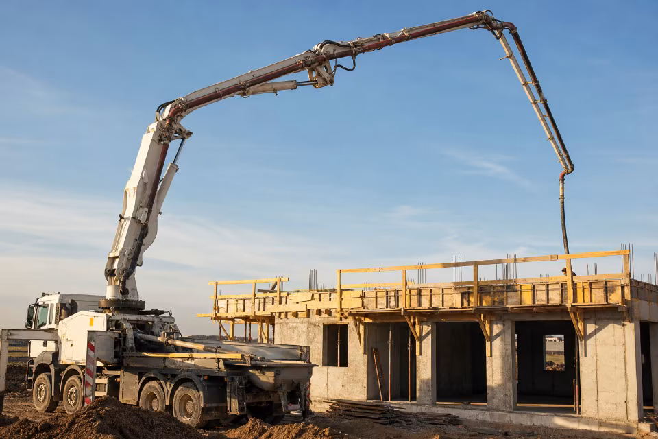 Autopumpa s teleskopskom strijelom isporučuje beton na gradilištu višespratne zgrade.