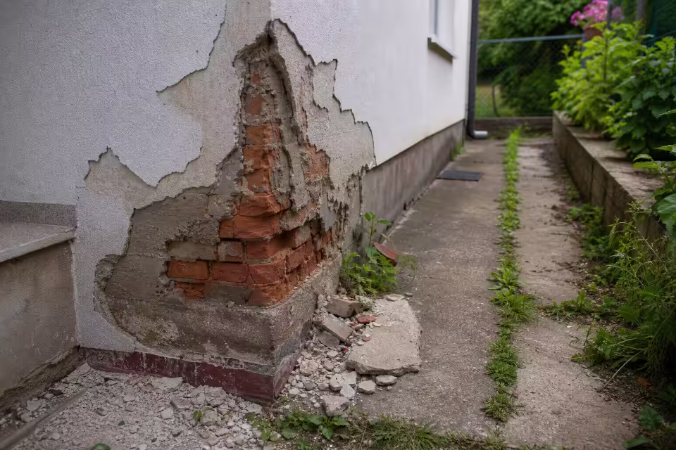 Majstor drži papirnatu ponudu i račun dok stoji u renoviranoj sobi — širi prikaz
