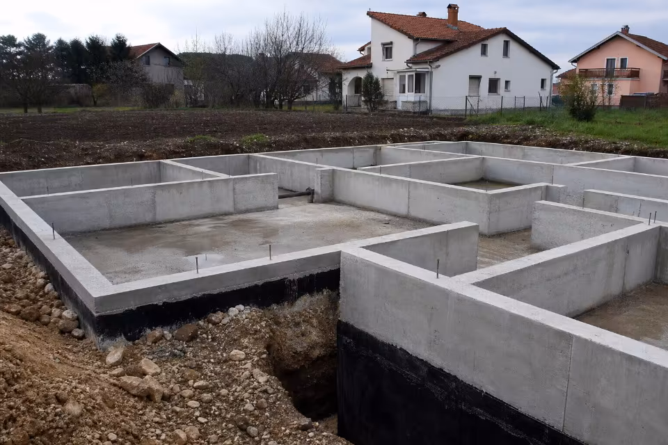 Radnici na gradilištu pripremaju armaturu za lijevanje betonskih temelja kuće — širi prikaz