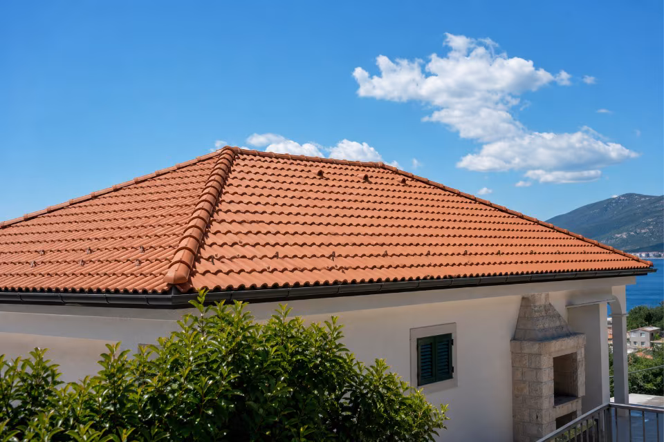 Gotov krov s crvenim crijepom na tradicionalnoj kući pod plavim nebom