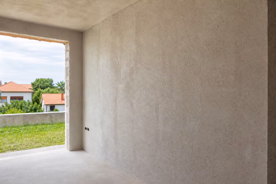 Radnik nanosi strojno žbukanje na zid tokom adaptacije stana — širi prikaz