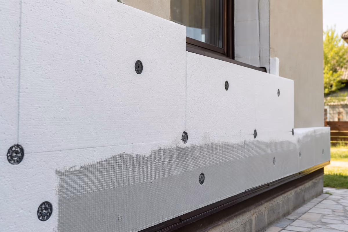 Radnici na skelama ugrađuju ploče stiropora na fasadu stambene zgrade — materijali i alat