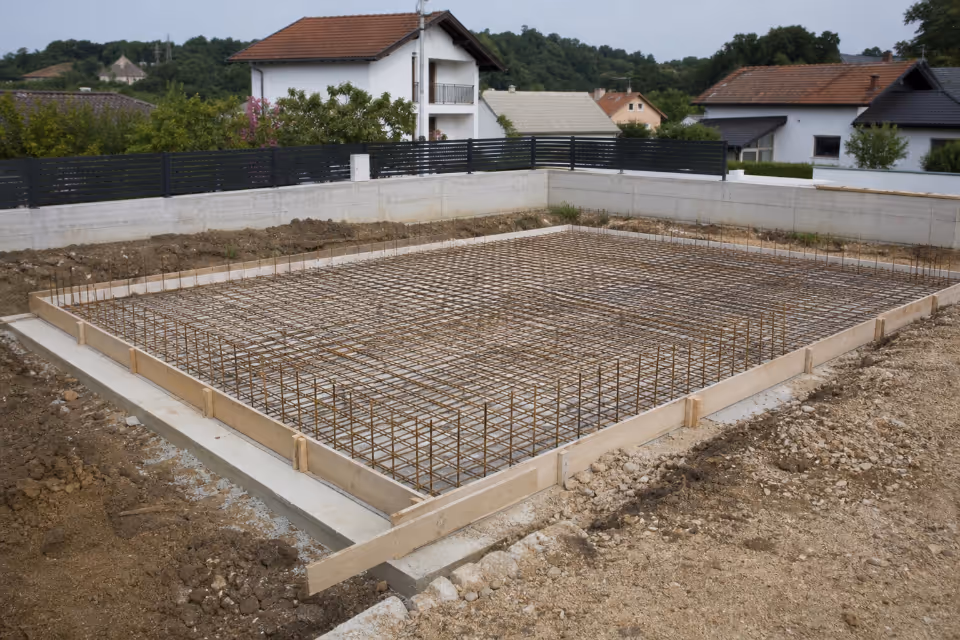 Betonska ploča temelja s armaturom i kalupom od dasaka pripremljena za izlijevanje betona na gradilištu.