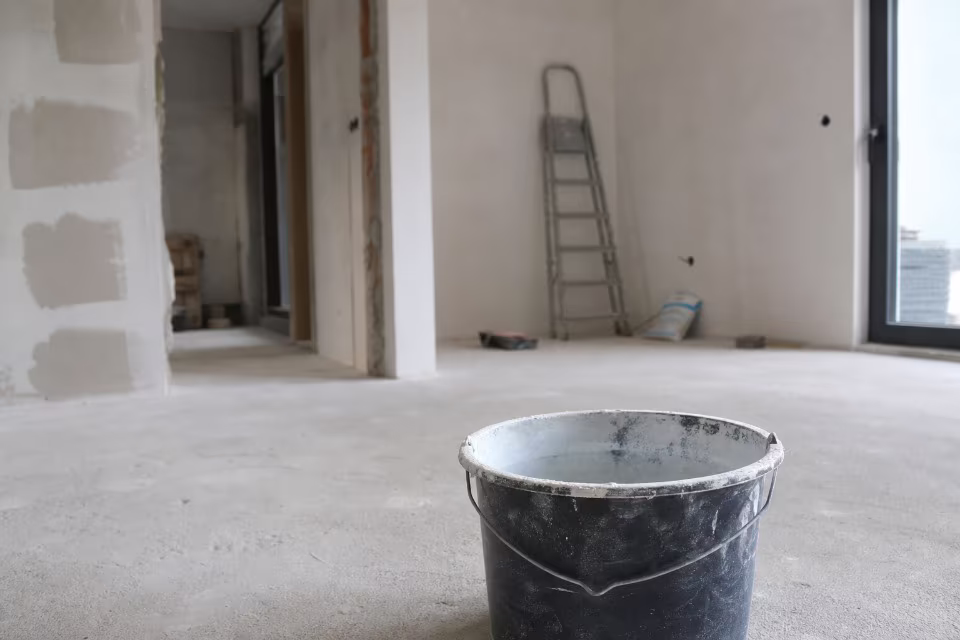 Majstor sa kalkulatorom i planovima renovacije na radnom stolu — širi prikaz