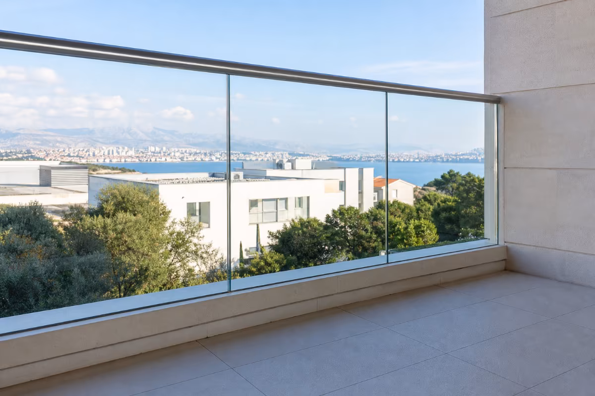 Moderan balkon sa providnom staklenom ogradom i metalnim rukohvatom, prirodno dnevno svjetlo