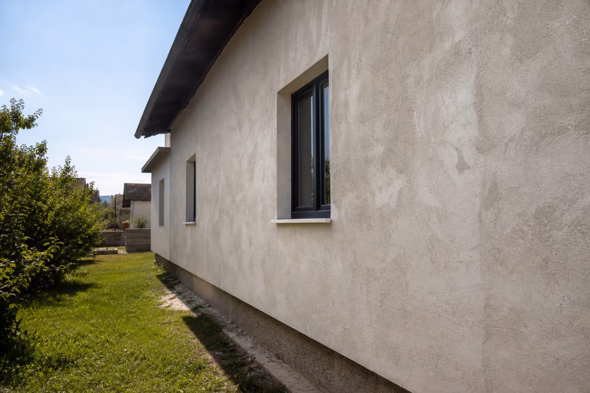 Radnik nanosi strojno žbukanje na zid tokom adaptacije stana — detalj izvedbe