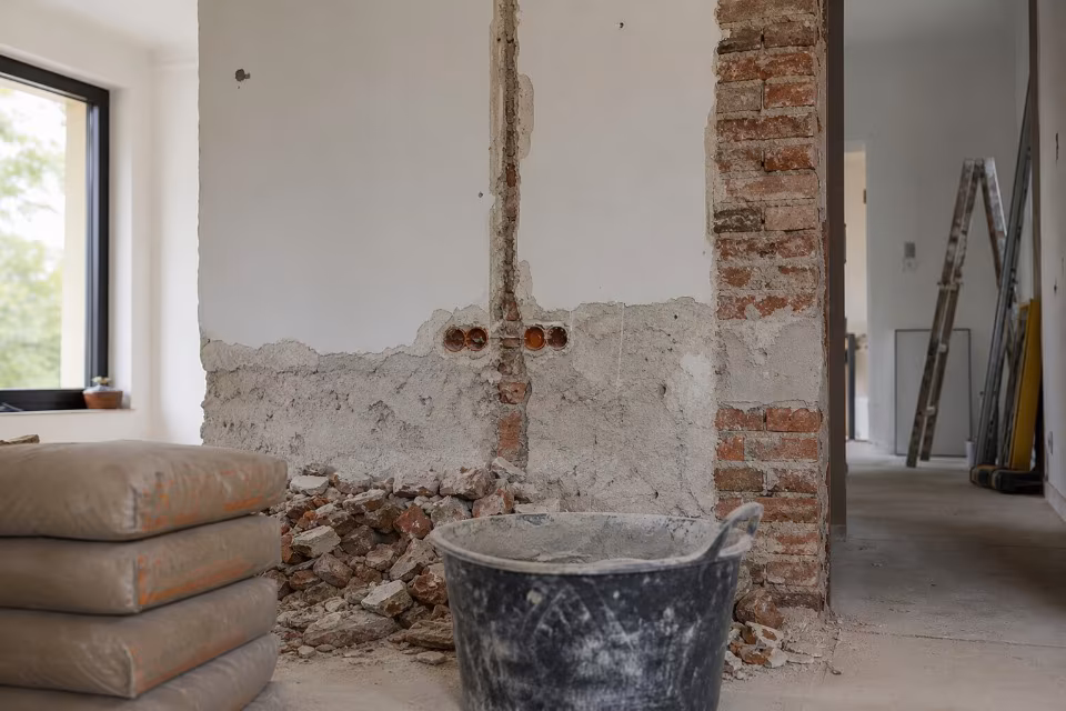 Kupac i majstor pregledavaju ugovor i planove na gradilištu — širi prikaz