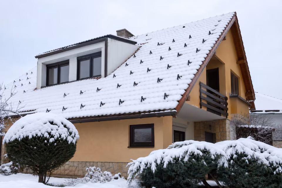 Kuća s crijepnim krovom i ugrađenim snjegobranima koji zadržavaju snijeg