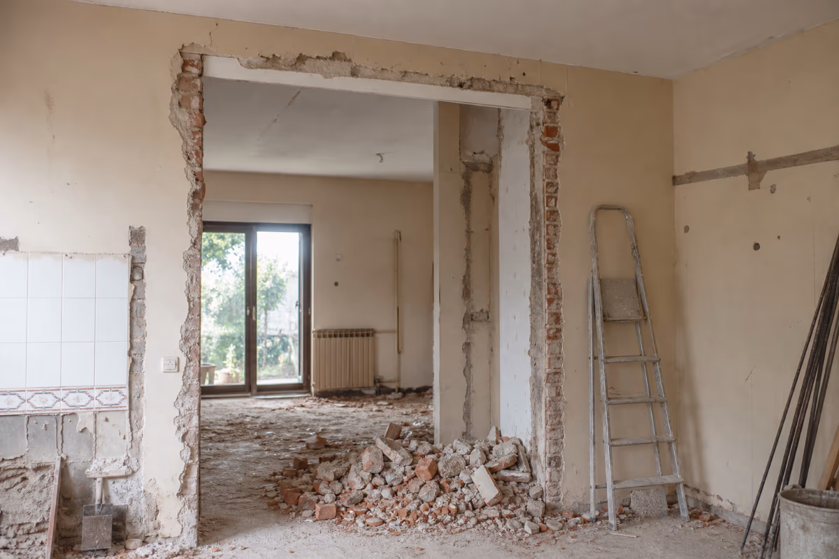 Radnik ruši pregradni zid čekićem u stanu tokom adaptacije — materijali i alat