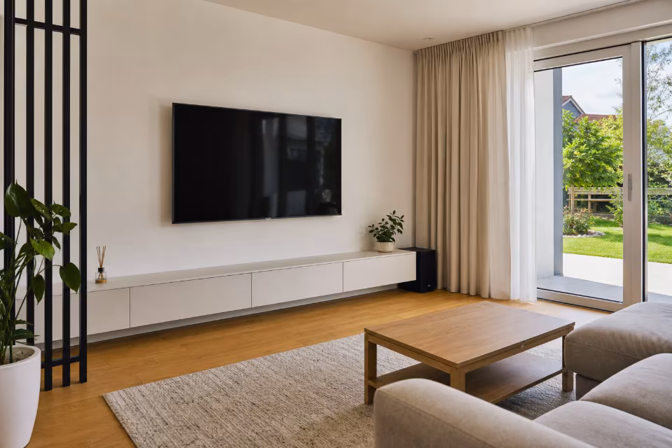 Veliki TV monitor obješen na bijeli gips-kartonski zid u modernoj dnevnoj sobi