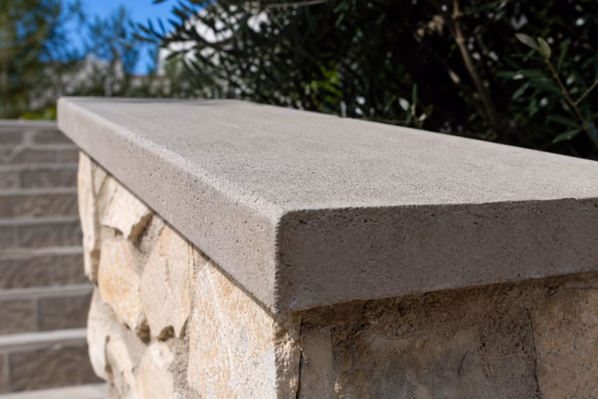 Detalj betonske pokrovne kape na vrhu kamene ograde s blagim nagibom prema van