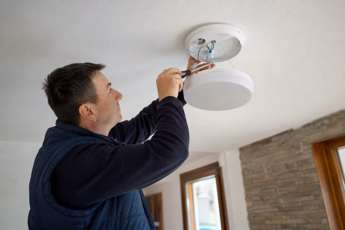 Električar montira moderni luster na stropu