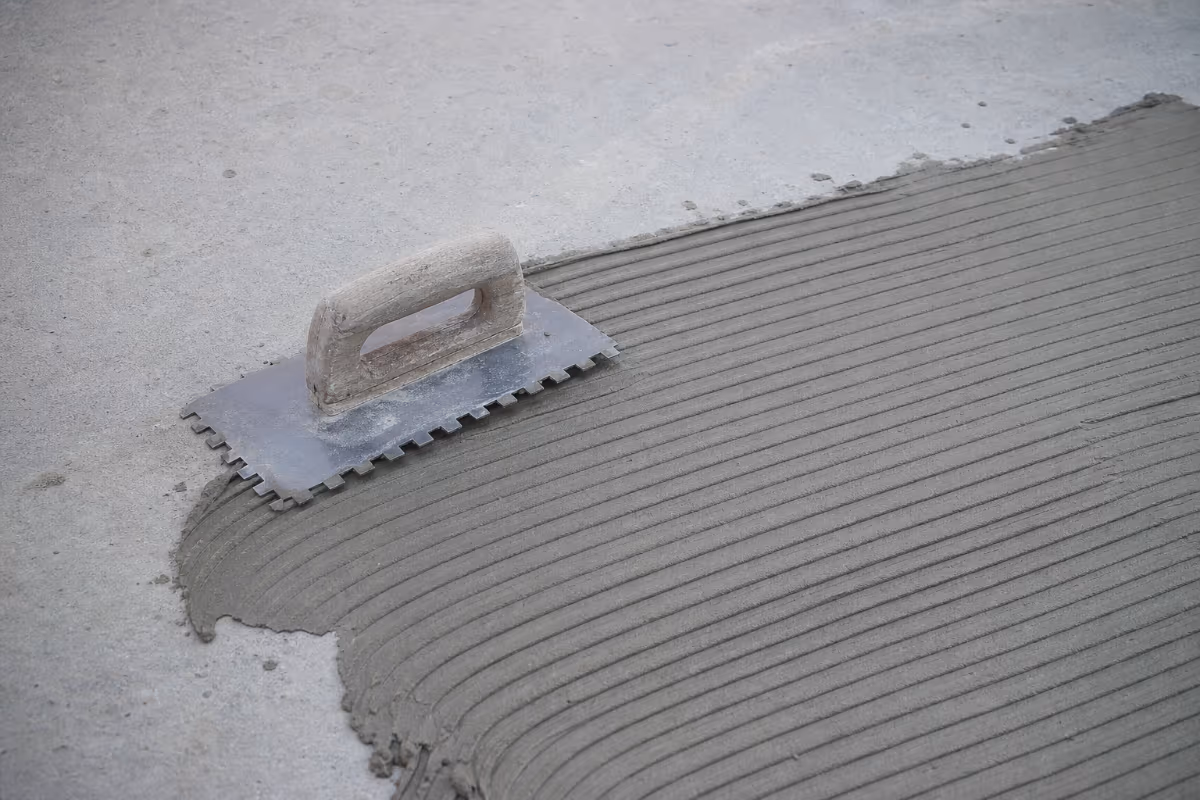 Detalj nanošenja lepka za pločice na betonsku podlogu pomoću nazubljene gletarice