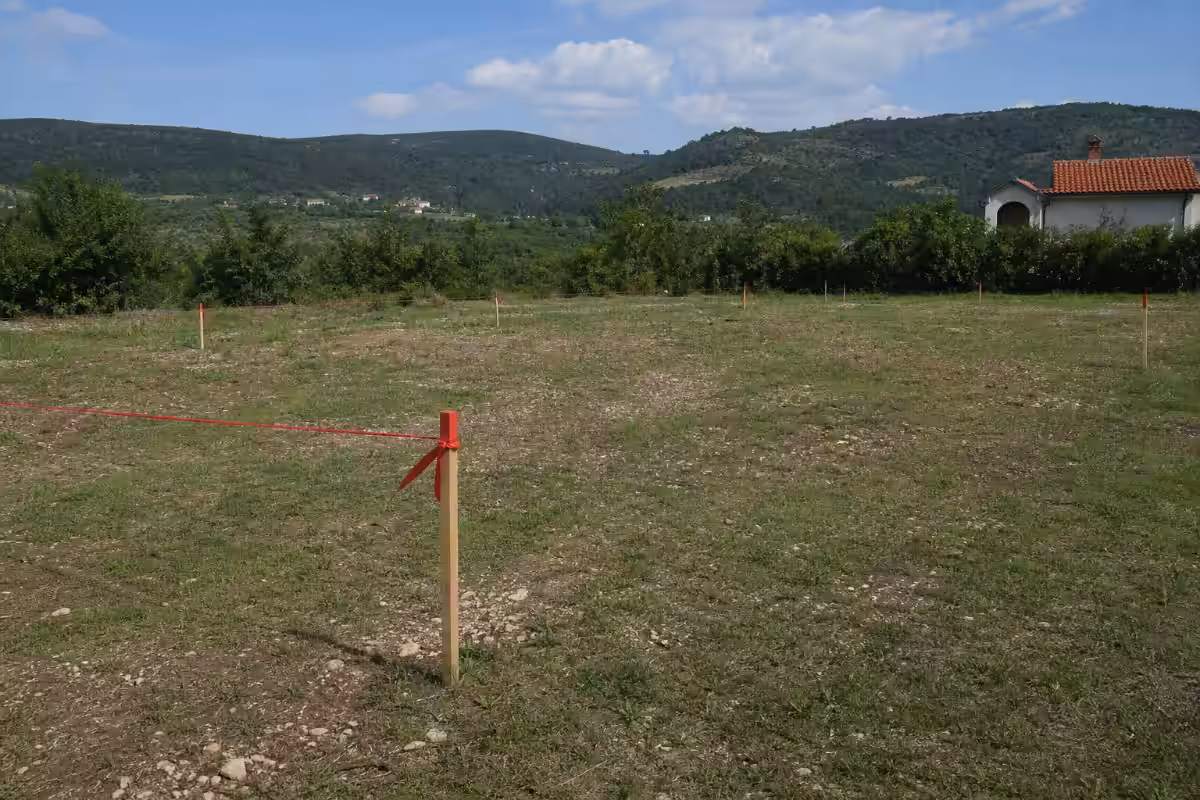 Prazna građevinska parcela sa označenim granicama i dokumentima na prvom planu